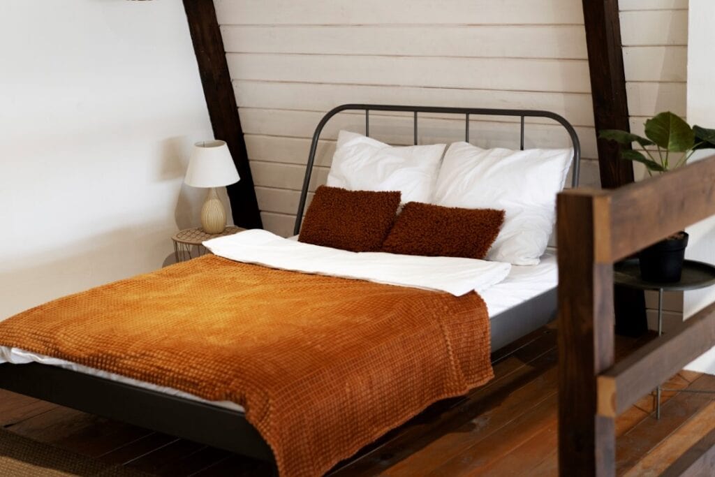 Double metal bed on wooden floor.