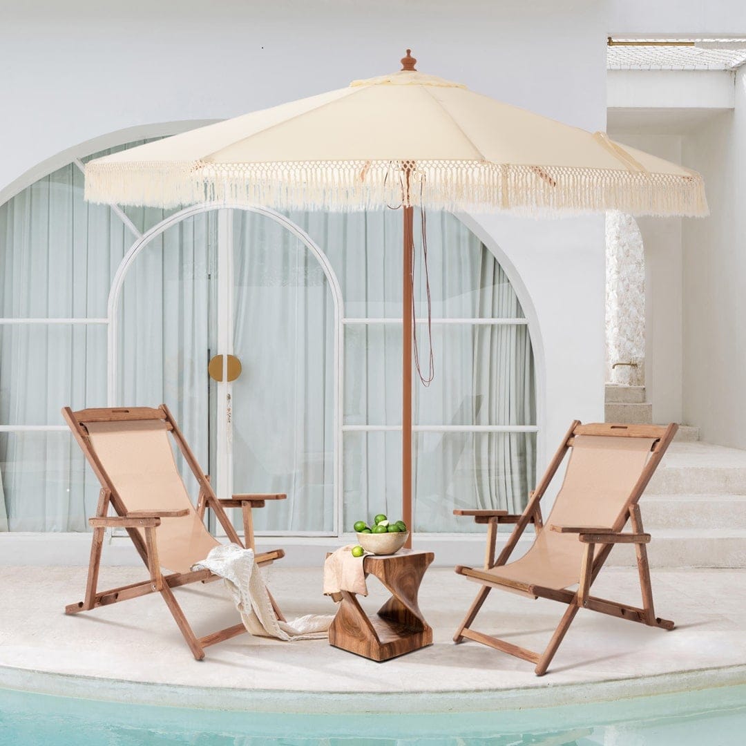 Wooden lounge chairs with large white umbrella next to house pool.
